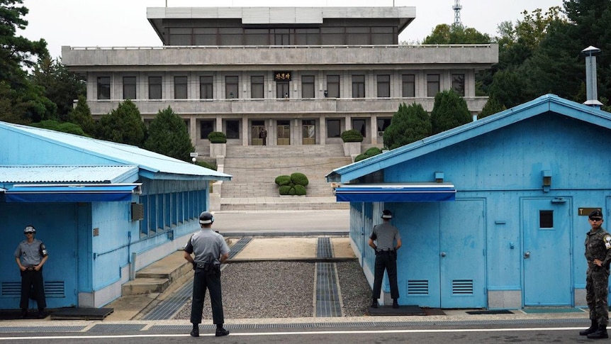 Soldiers stand with their backs facing the camera in the DMZ's Joint Security Area