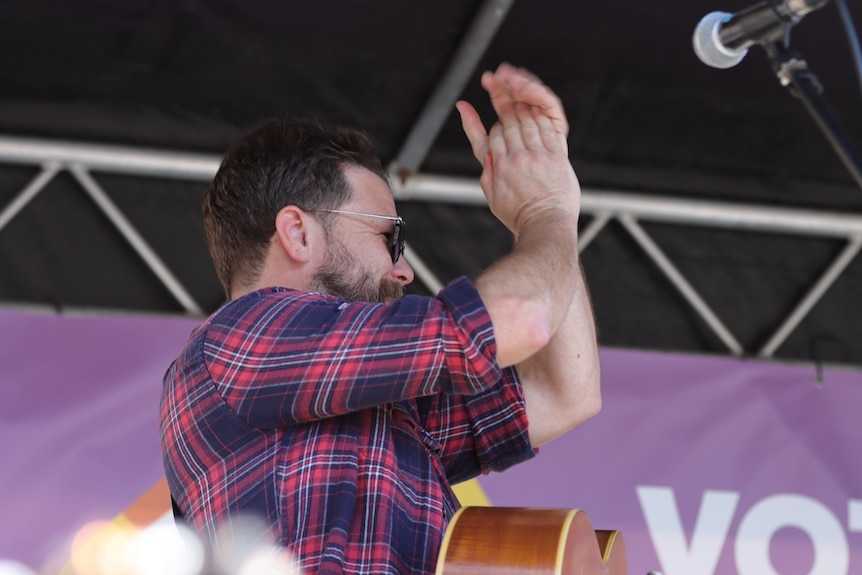 Tom Busby from Busby Marou claps his hands on stage at a performance in Brisbane.