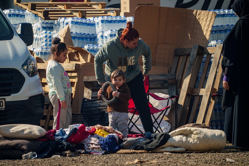 Two small children play near crates of water bottles