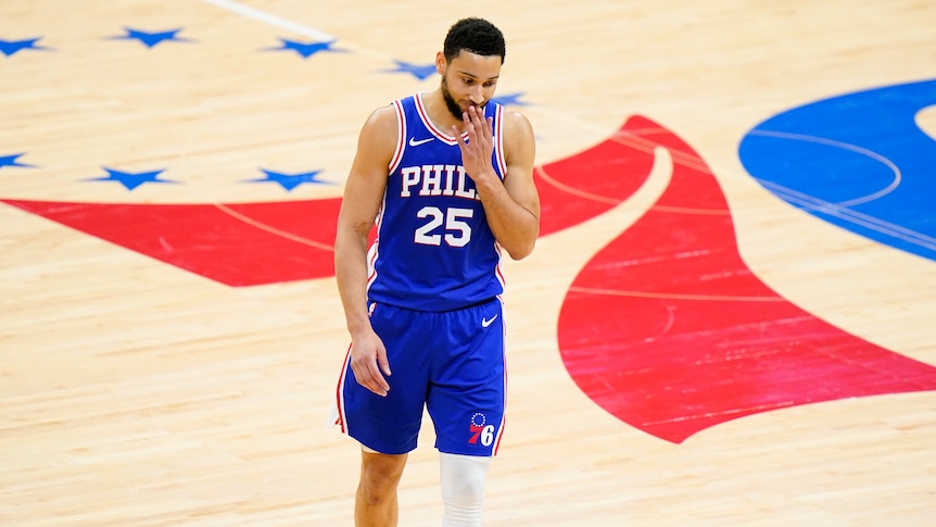 Man standing in the middle of a basketball court looking sad after a match 