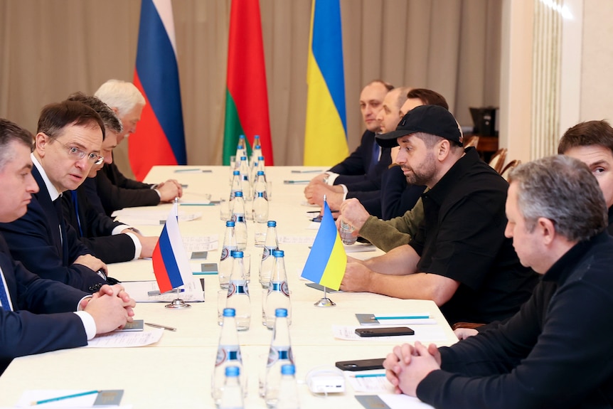 Men sit on either side of a long table