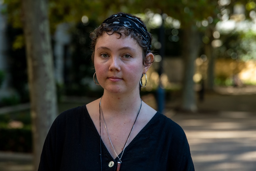 Young woman standing on path in shade with trees in background