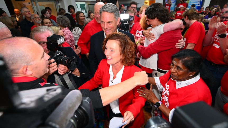 Jodie Belyea and Richard Marles celebrating in a group of people wearing red. 