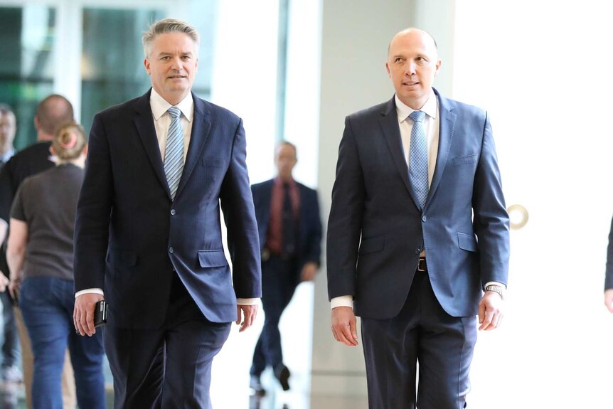 Peter Dutton and Mathias Cormann walk down a  parliament hall