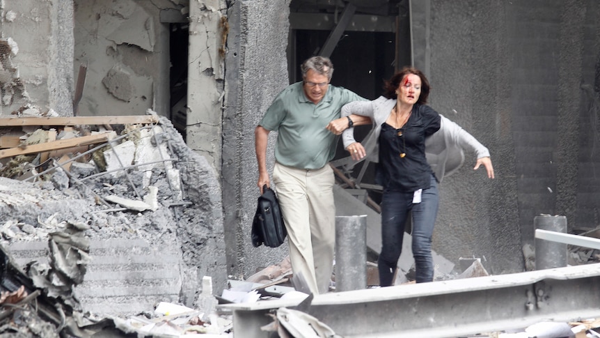 An injured woman is helped by a man at the scene of a powerful explosion that rocked central Oslo (Reuters: Morten Holm)