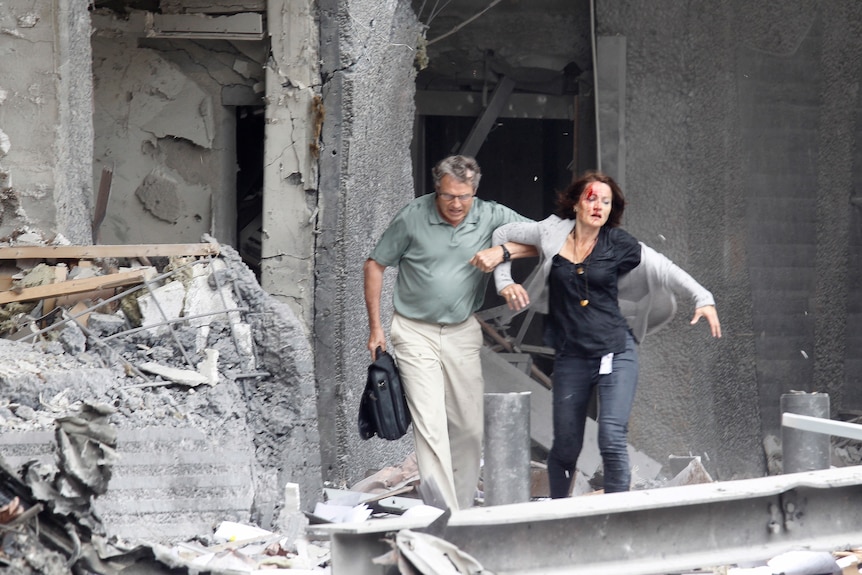 An injured woman is helped by a man at the scene of a powerful explosion that rocked central Oslo (Reuters: Morten Holm)