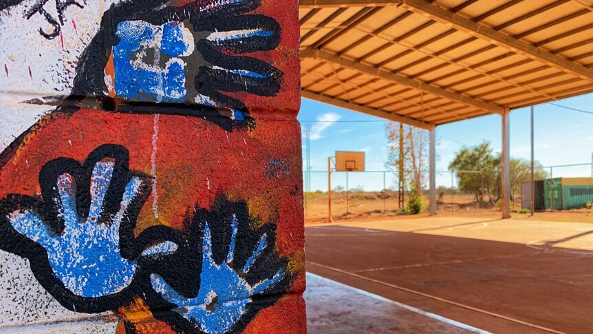 Hands painted on the wall of a building next to a basketball court.