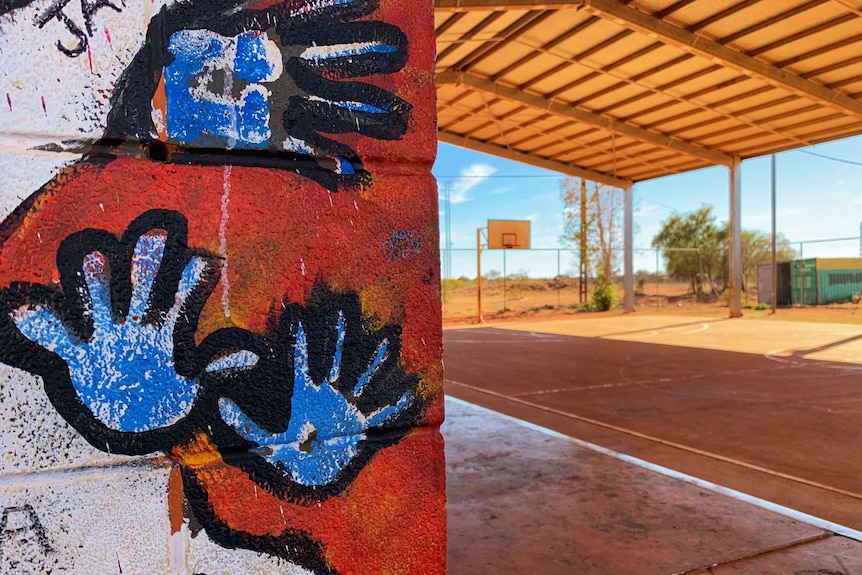 Hands painted on the wall of a building next to a basketball court.