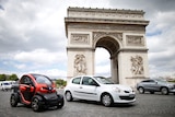 Twizy electric car (L) of French car manufacturer Renault, drive past the Arc de Triomphe in Paris.