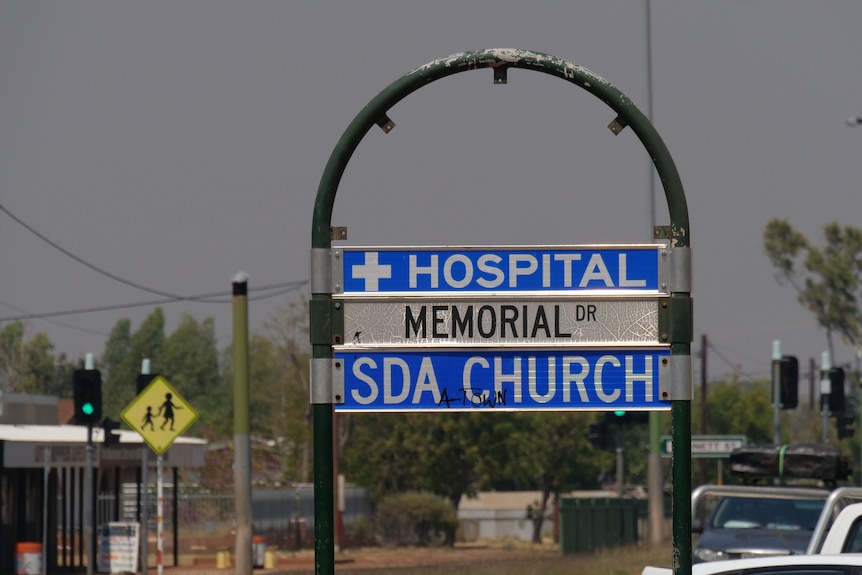 A cloudy sky in the background with a sign in the foreground which reads "hospital"