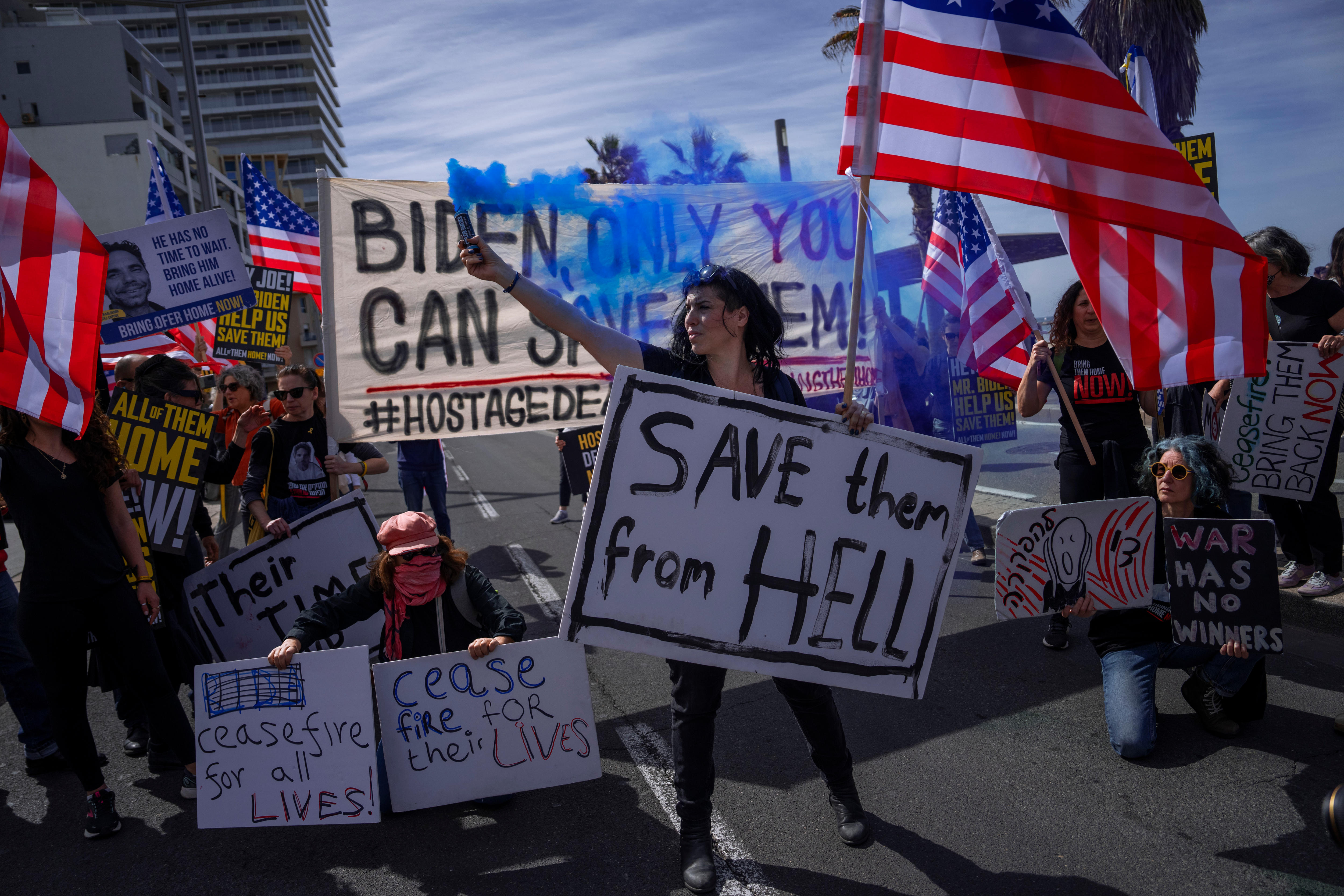 A group of protesters on a road holding up signs and US flags.