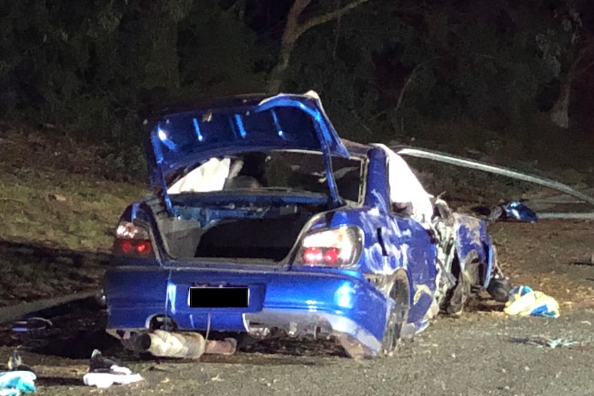 A smashed up blue car after a fatal accident.  