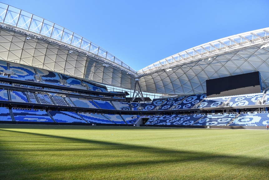 A large blue and white grandstand with pristine grass before it