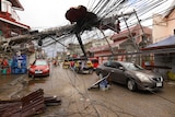 Cars pass by a toppled electrical post