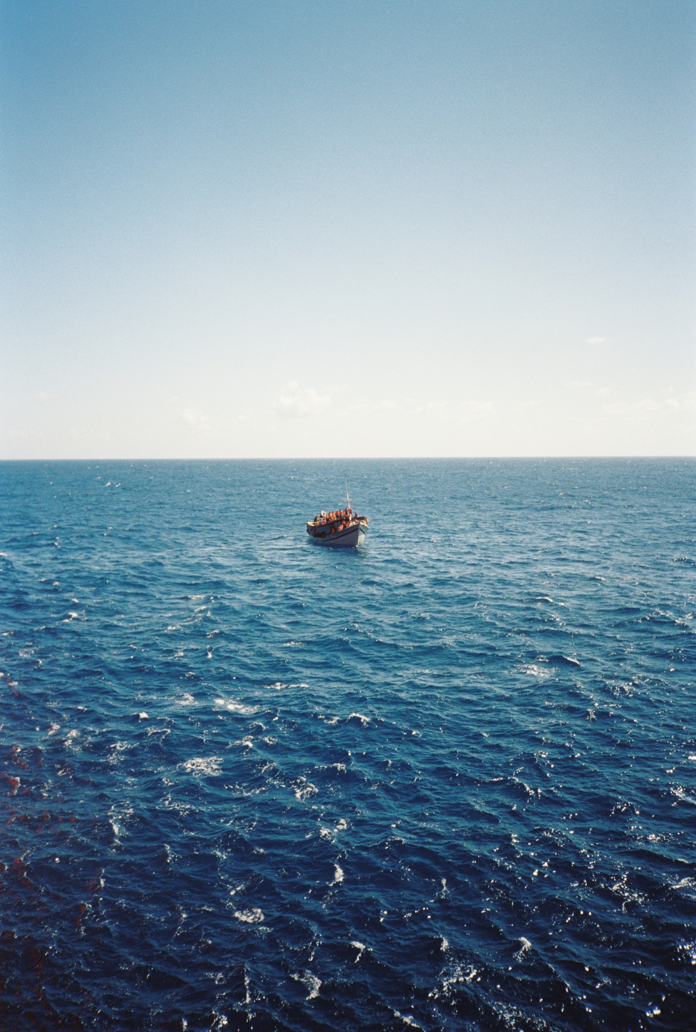 A small wooden boat bobs in the open ocean.
