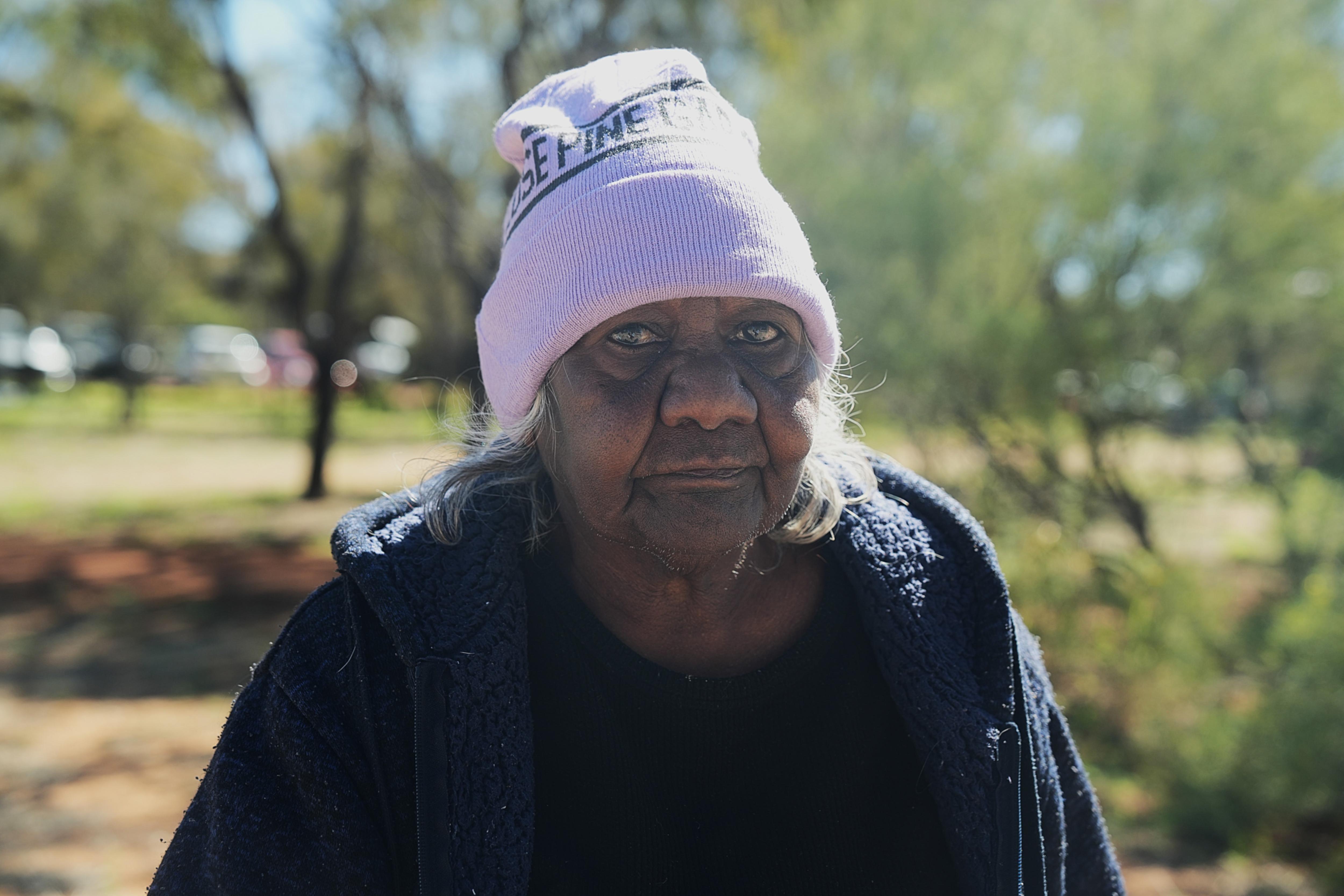An older woman wearing a pink beanie.