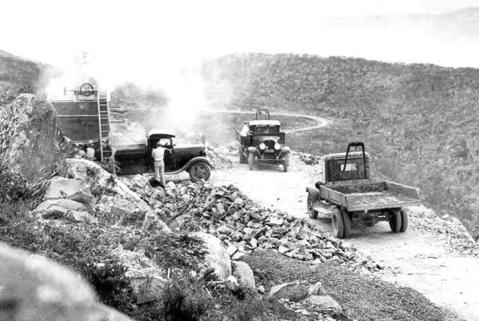 Old photo of trucks on road construction site.