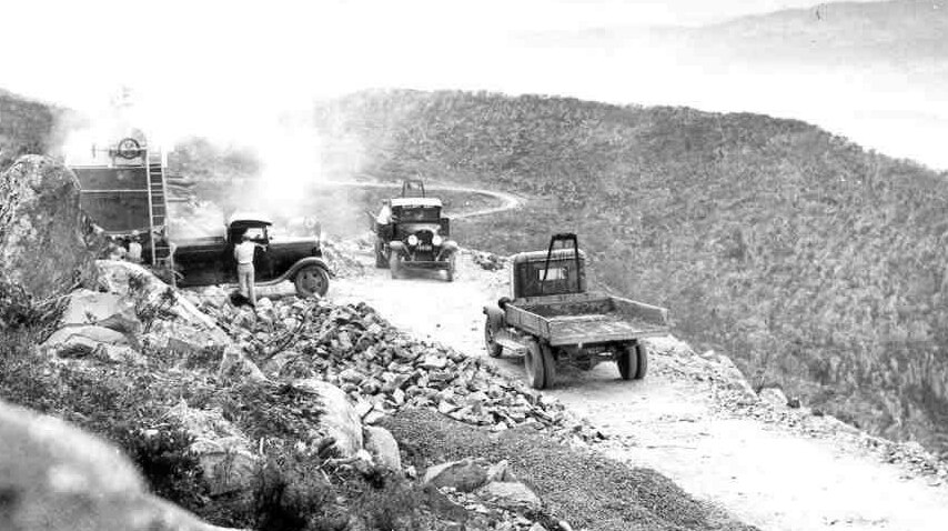 Old photo of trucks on road construction site.