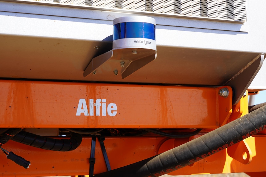 A close up of a blue and white sensor on a machine, Alfie is painted on the orange machine.