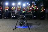 A drone in the foreground in front of a group of mine workers in high-vis gear
