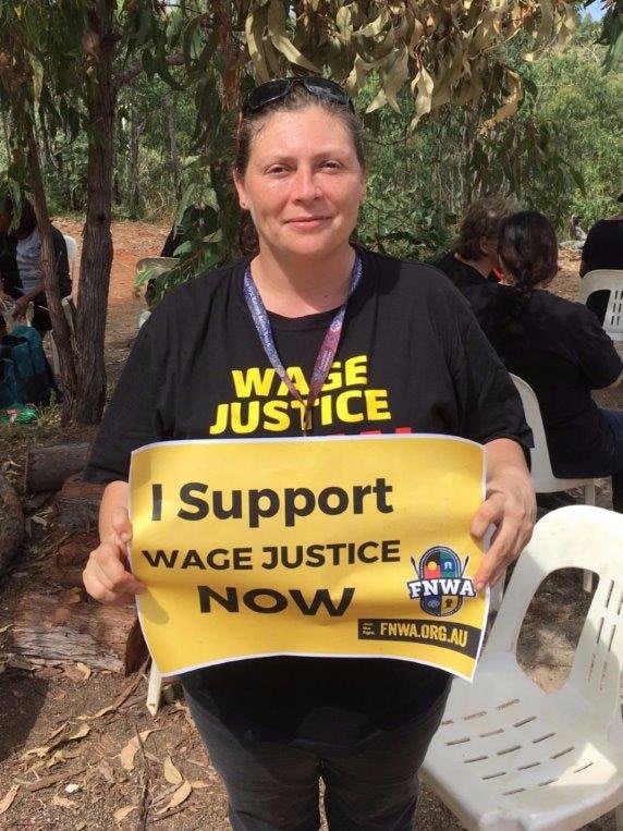 Lara Watson holding a sign that reads 'I support wage justice now'