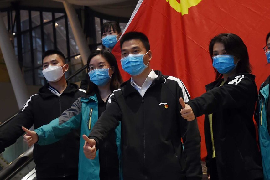 Medical workers from outside Wuhan pose for pictures with a Chinese Communist Party flag