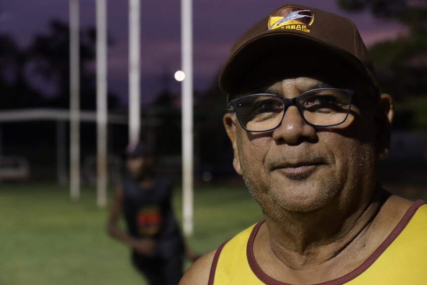Steve Raymond looks at the camera at the footy oval at night.