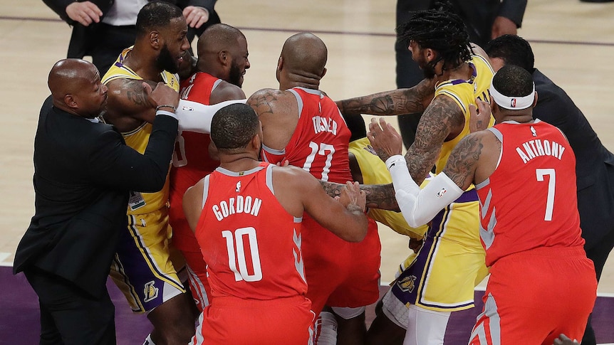 A group of men wearing yellow and red singlets push each other