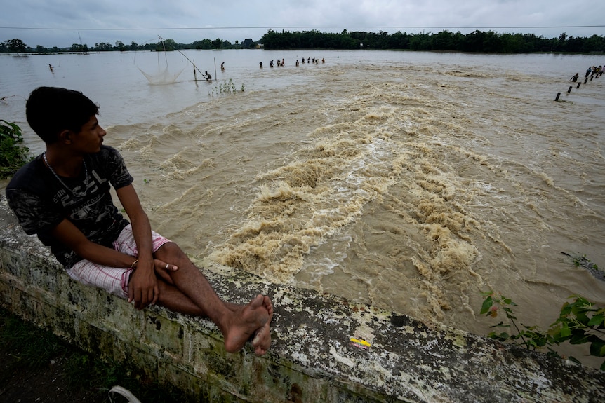 A boy watches people fishing in floodwaters in Korora village.