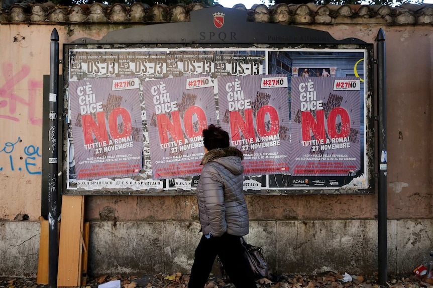 A woman walks past posters in support of the 'No' vote in the upcoming constitutional reform referendum in Rome, Italy.