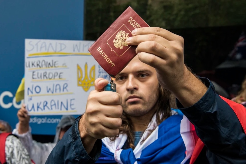 A man burns a Russian passport, amid a pro-Ukraine rally in Sydney.