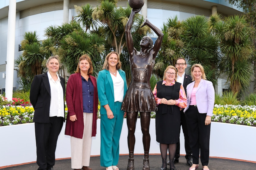 Sharelle McMahon stands alongside a statue of herself as well as various other netball administrators