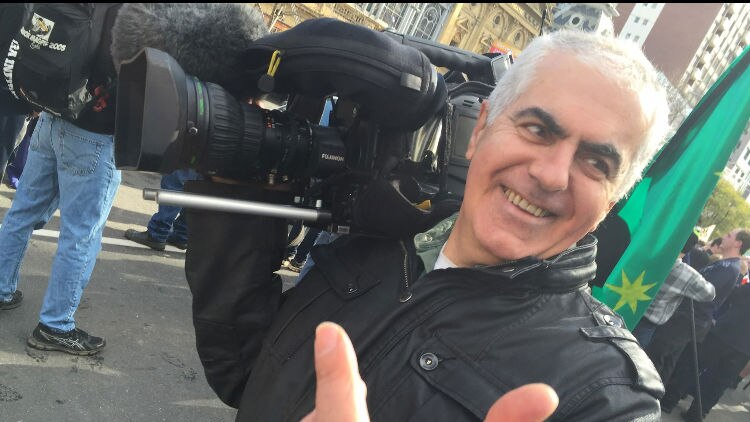 Vince Tucci holding camera while covering a demonstration.