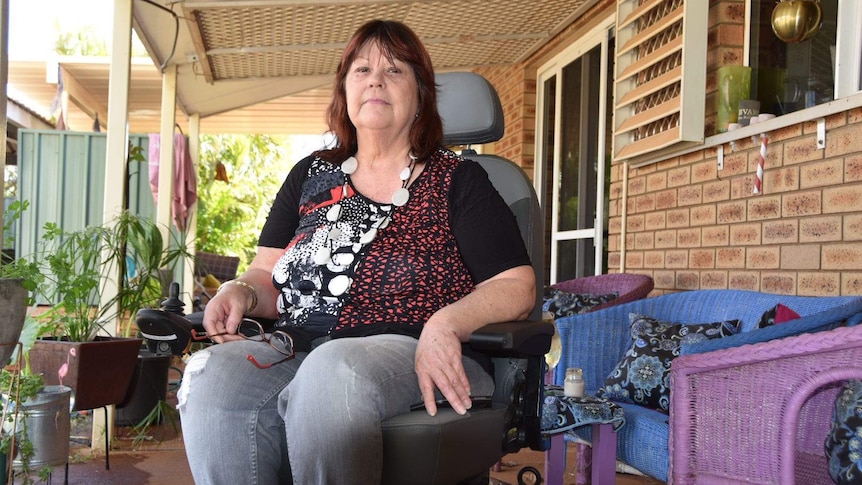 A woman sits in a wheelchair on a verandah