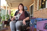 A woman sits in a wheelchair on a verandah
