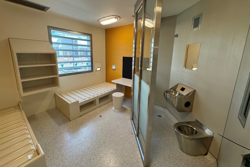 A prison cell with two beds and a bathroom.