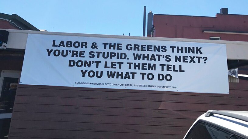 Pro-pokies signage hanging off a hotel exterior wall.