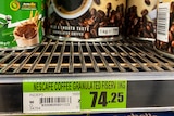A sign in a supermarket that says the price of coffee is $74. 
