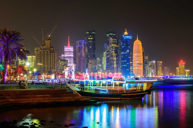 Doha's CBD skyline is illuminated with colourful lights over the buildings.