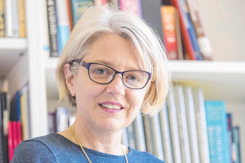 Headshot of Dr Emma McBryde, holding a book.