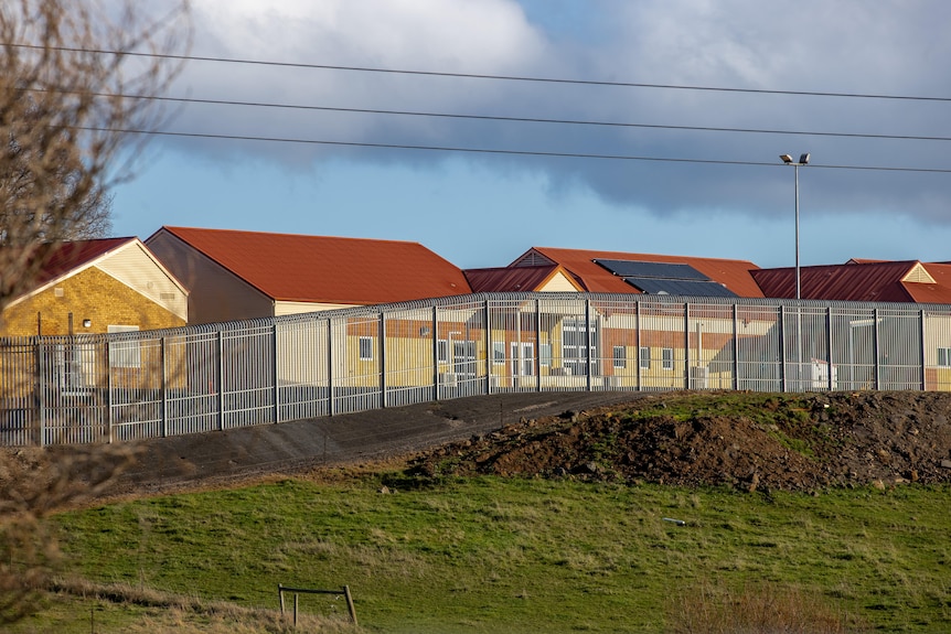 The buildings of the Ashley Youth Detention Center sit behind a tall fence.