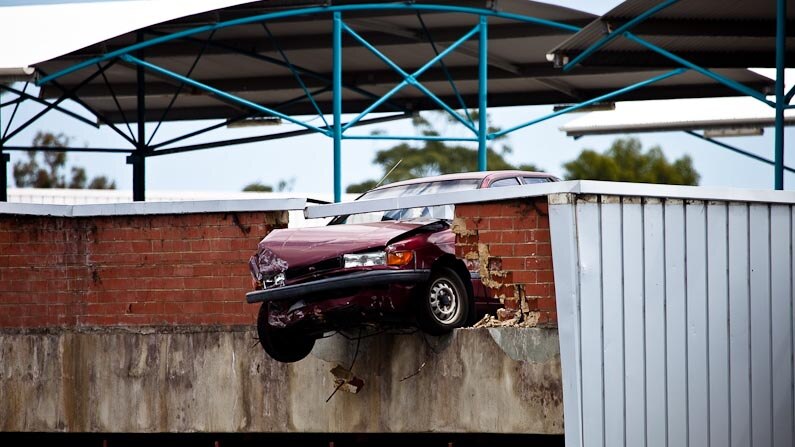 Precarious predicament for a car after it crashed through a barrier at a shopping centre carpark.