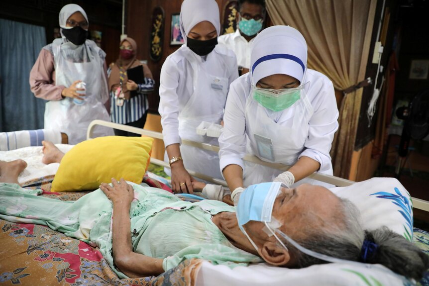 A healthcare worker administers a vaccine to an elderly woman at her home