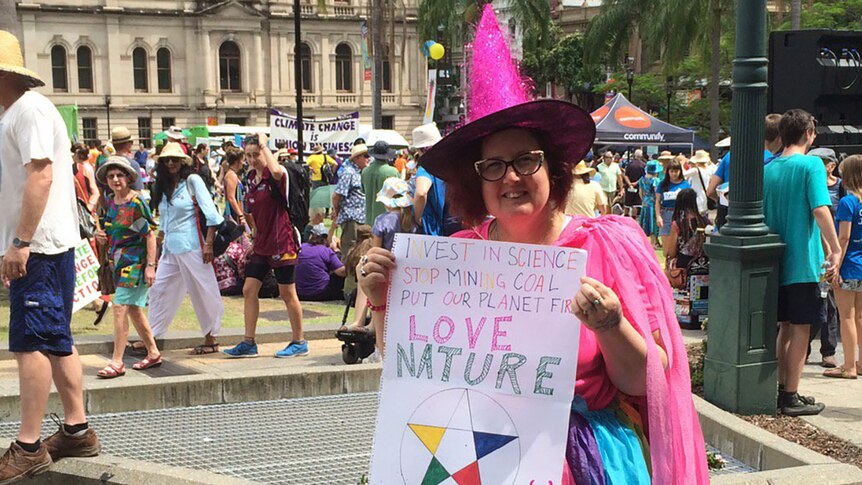 Wanda Vanderwolf at the Brisbane climate rally dressed in a pink witch's hat and shirt, holding a banner saying love nature
