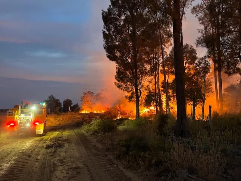 A fire truck parked next to flames from a bushfire at Moonie