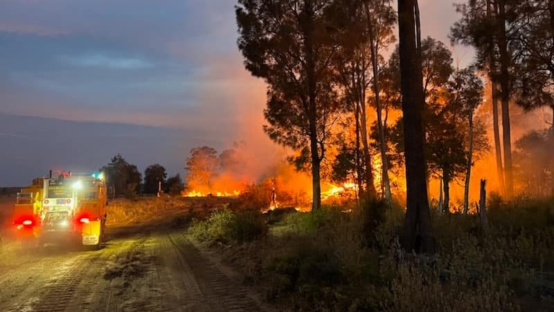 A fire truck parked next to flames from a bushfire at Moonie