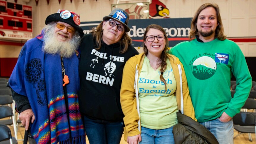 A group of Democrat supporters wearing Bernie Sanders shirts, stickers and badges stand and stare at the camera.