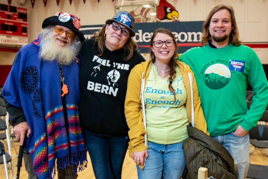 A group of Democrat supporters wearing Bernie Sanders shirts, stickers and badges stand and stare at the camera.