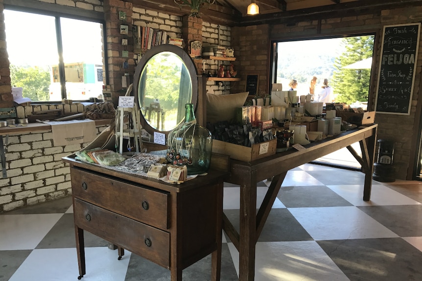 A trendy farm shop with the floor painted in black and white squares, an antique dresser and table covered with artisan products