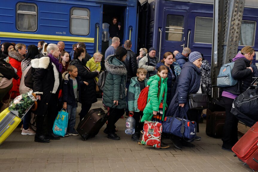 A crowd of people disembark from a train